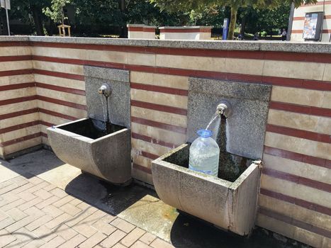 Locals in town to gather water from a public drinking fountain with fresh water.