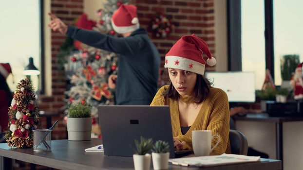 Portrait of festive employee using laptop in office with seasonal decorations