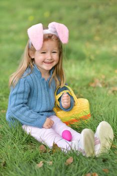 Girl with bunny ears collects chocolate eggs for Easter