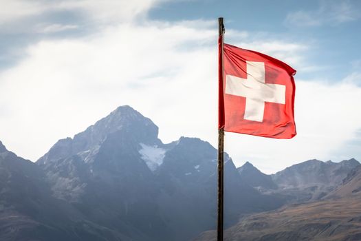 Swiss flag and Bernina mountain range with glaciers in the Alps, Switzerland