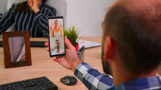 Financial businessman having a videomeeting talking with company manager and executive administrator sitting on desk in corporate building office. Entrepreneur using modern technology.