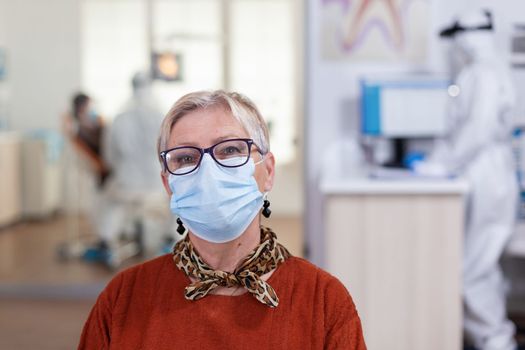 Portrait of retired patient in dental office looking on camera wearing face mask