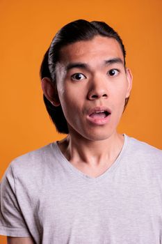 Surprised young adult asian man facial expression close up