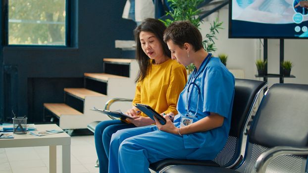 Medical assistant consulting asian woman in hospital lobby
