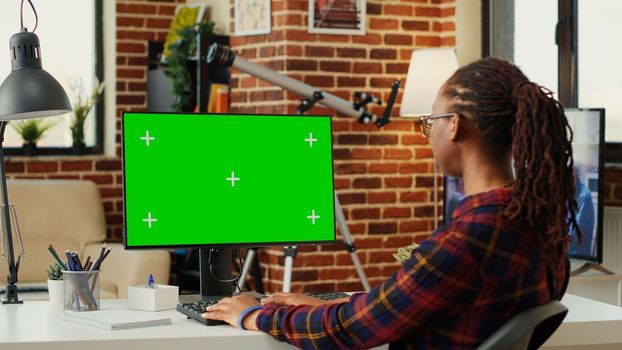 African american woman looking at computer with greenscreen