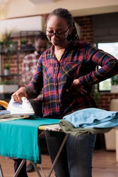 Happy African american woman takes care of clothes ironing