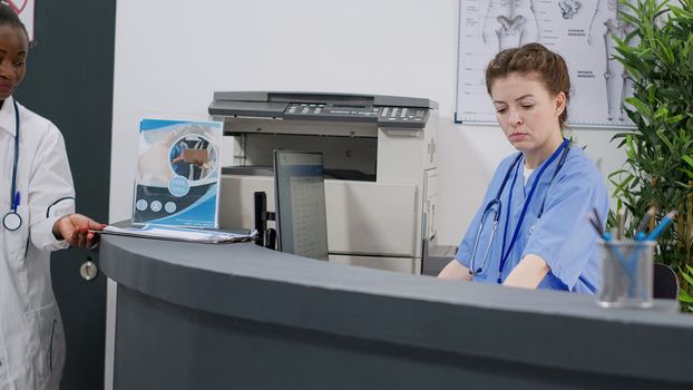Medical assistant working at hospital reception desk in facility