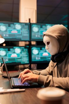 Scary male scammer wearing mask hacking database