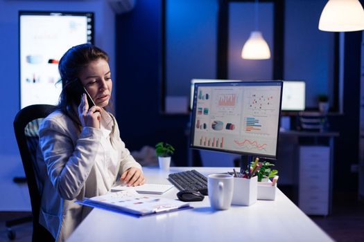 Businesswoman speaking at smartphone with her teamate while working at computer