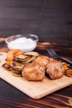 Grilled chicken next to fried zucchini and sweet potatoes