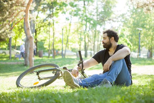 Man looking away while resting on the grass in the park