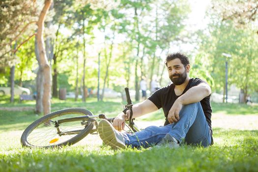 Bearded man next to his bicycle resting on the ground