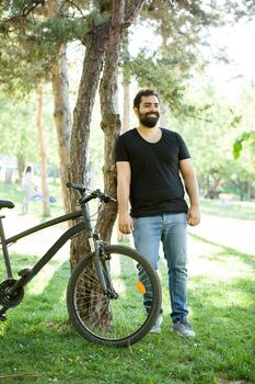 Smiling bearded man leaning on a tree in the park