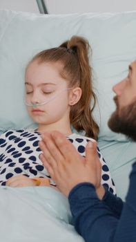 Sick daughter sleeping while worried sad father praying for heath care recovery