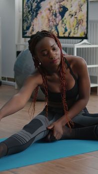 Flexible fit black woman doing stretching routine on yoga map