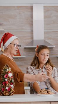 Grandmother watching xmas online video with granddaughter on tablet while grandfather bringing milk