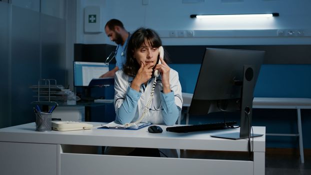 General practitioner woman sitting at desk while talking with remote patient