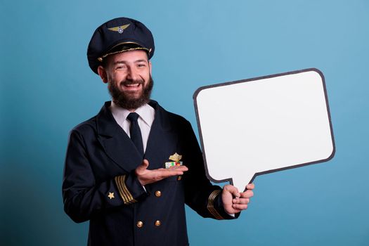 Smiling airplane aviator holding white blank speech bubble