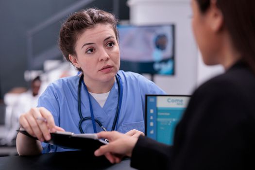 Nurse showing patient expertise to receptionist discussing disease symptoms
