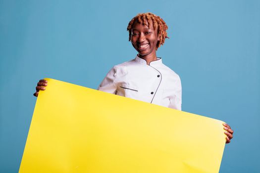 Young afro chef showing a sign