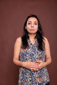 Indian woman with neutral facial expression, intertwined fingers portrait
