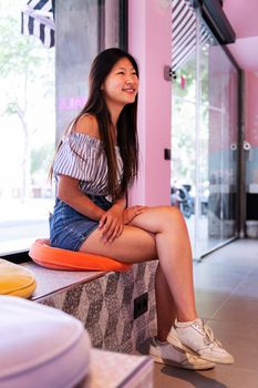 smiling young asian woman waits her turn sitting in the beauty salon, body care and wellness concept