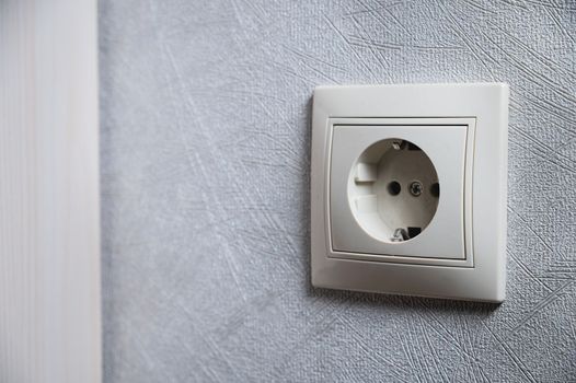 White socket alone on the wall inside the house, close-up