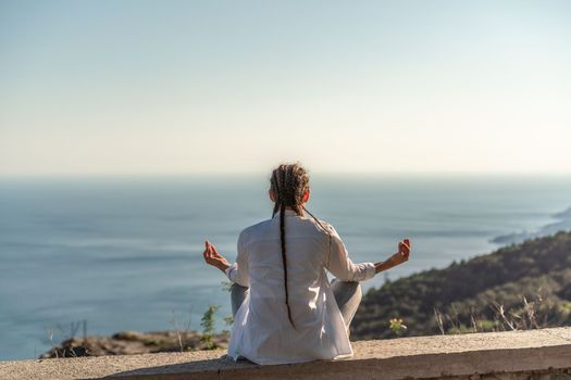 woman doing yoga in the top of a cliff in the mountain. Woman meditates in yoga asana Padmasana.
