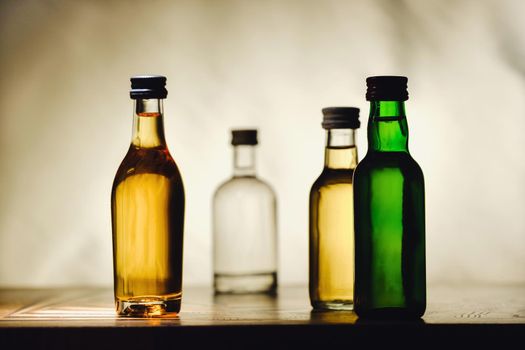 different alcohol bottles are on the table on a light background