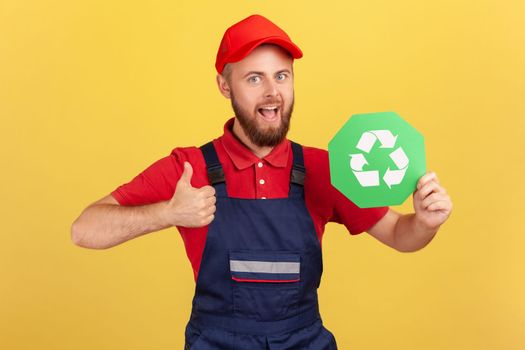 Worker man standing and holding recycling sign, thinking green, showing thumb up.