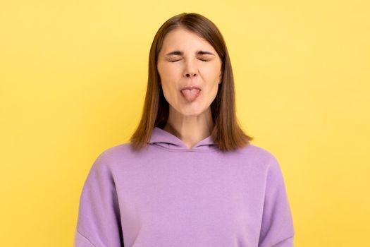 Woman demonstrating tongue, behaving naughty unruly, childish mood, closed eyes.