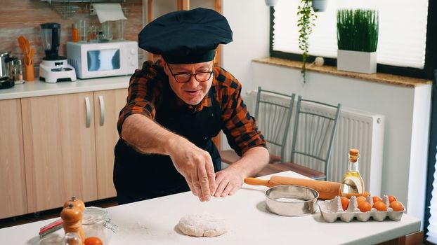 Professional chef sprinkling flour on dough