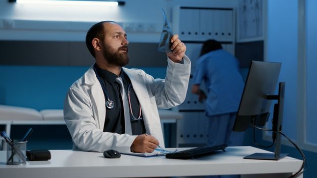 Physician doctor analyzing radiography typing medical expertise on computer