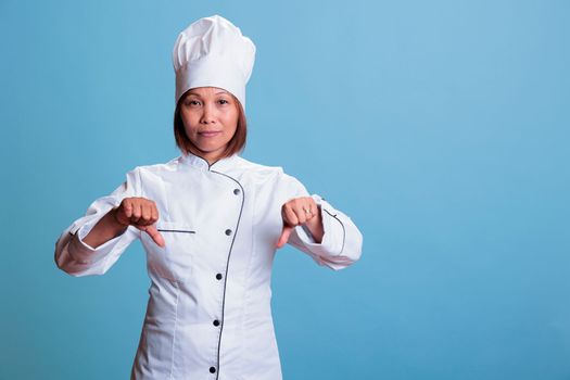 Senior asian cook wearing kitechen uniform doing dislike sign