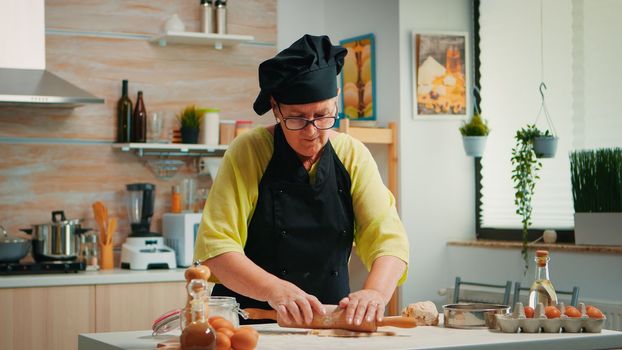 Woman chef using wooden rolling pin