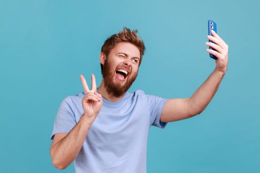 Man taking selfie or talking on video call and showing victory peace gesture, pleasant communication