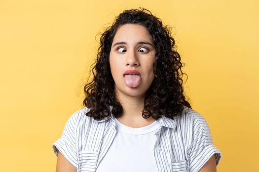 Woman standing with crossed eyes and tongue out, childish behavior, having foolish facial expression