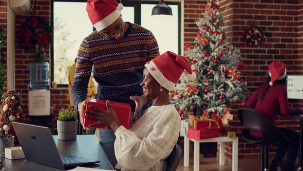African american coworkers exchanging gifts in festive decorated office