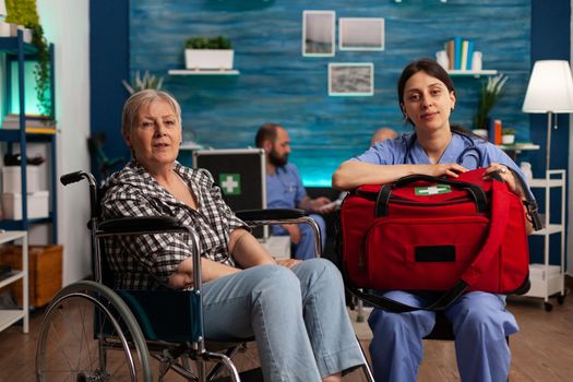 Portrait of female nurse and elderly woman in wheelchair