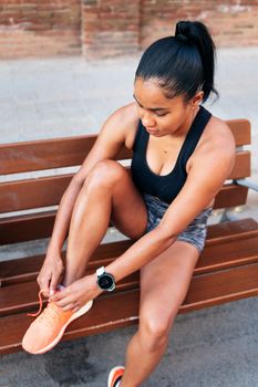 latin sportswoman lacing up her running shoes