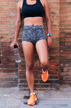 athlete with a water resting against a brick wall
