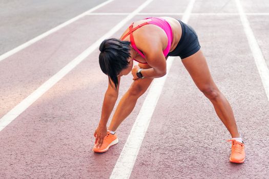 sportswoman stretching legs on the athletics track
