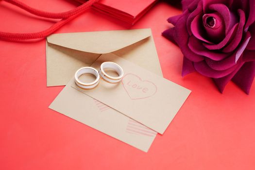 wedding ring and gift box and rose flower on red