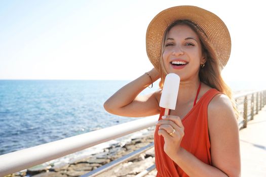 Attractive Brazilian woman eating a lemon popsicle looking at the camera on summer