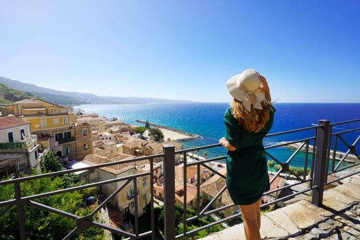 Holidays in Italy. Tourist woman with straw hat enjoying view of Pizzo village from terrace in Calabria, Italy.