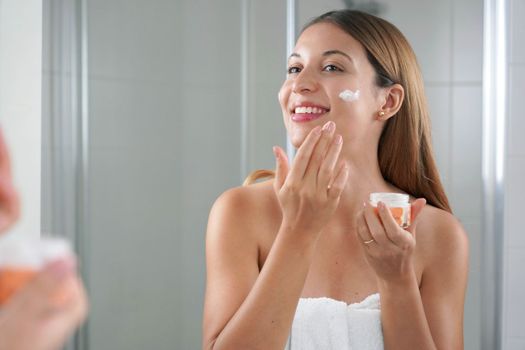 Skincare woman applying cream on her cheek. Face moisturizing nourishing invigorating treatments. Enjoying relaxing time.