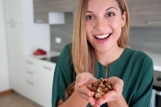 Beautiful healthy woman showing mix of nuts seeds dried fruit at the camera