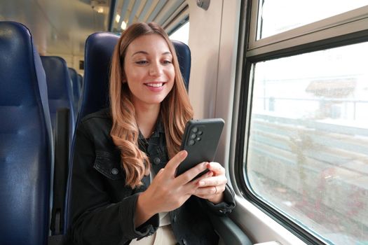 Young business woman using public transport, sitting with phone on train