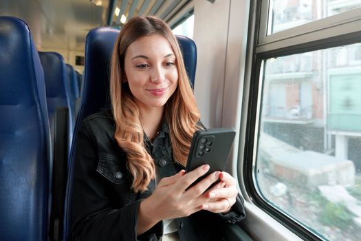 Beautiful student girl sitting on train using smartphone