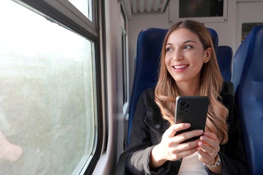 Portrait of young satisfied woman traveling with public transport holding mobile phone sitting and relaxed thoughtless